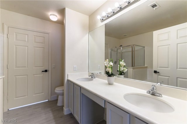 bathroom with hardwood / wood-style flooring, vanity, walk in shower, and toilet