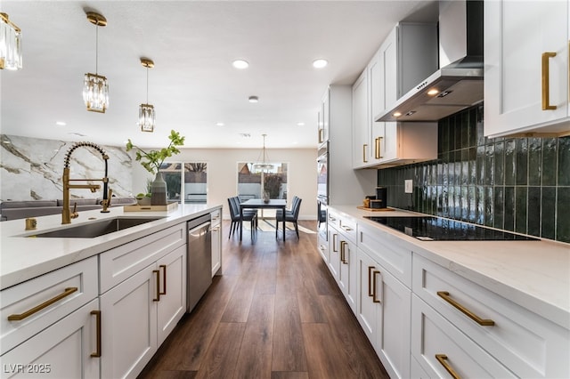 kitchen with sink, white cabinetry, appliances with stainless steel finishes, pendant lighting, and wall chimney range hood