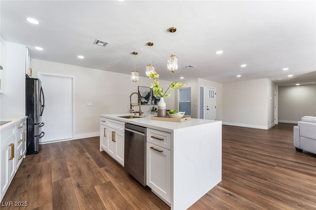 kitchen with pendant lighting, sink, stainless steel appliances, white cabinets, and a center island with sink