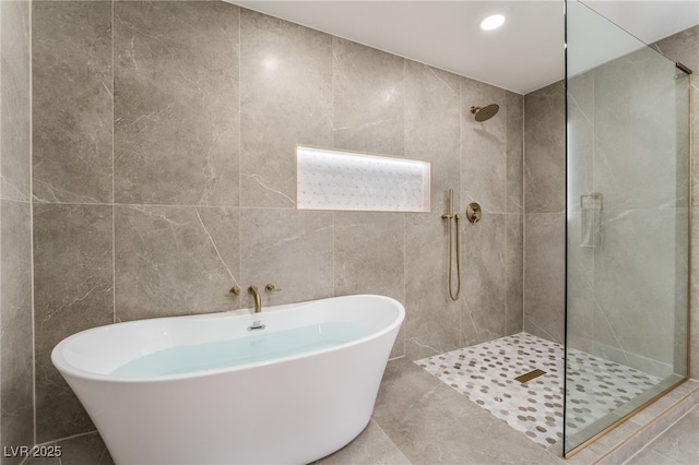 bathroom featuring tile walls and plus walk in shower