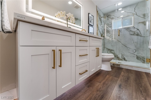 bathroom with vanity, hardwood / wood-style floors, a shower with door, and toilet