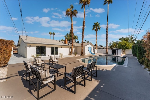 view of swimming pool featuring a storage shed, a water slide, and a patio