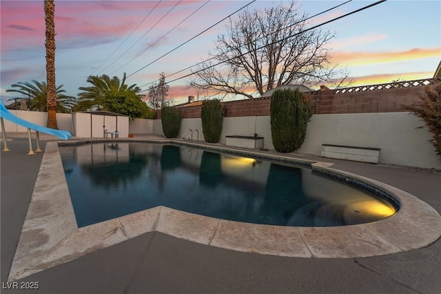 pool at dusk with a storage unit and a water slide