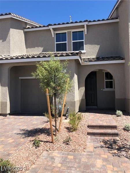 view of front of property with a garage, a tiled roof, and stucco siding