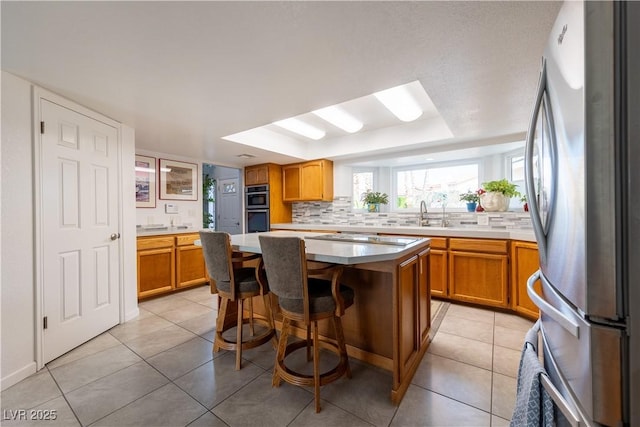 kitchen featuring tasteful backsplash, light tile patterned floors, a kitchen breakfast bar, a kitchen island, and stainless steel appliances