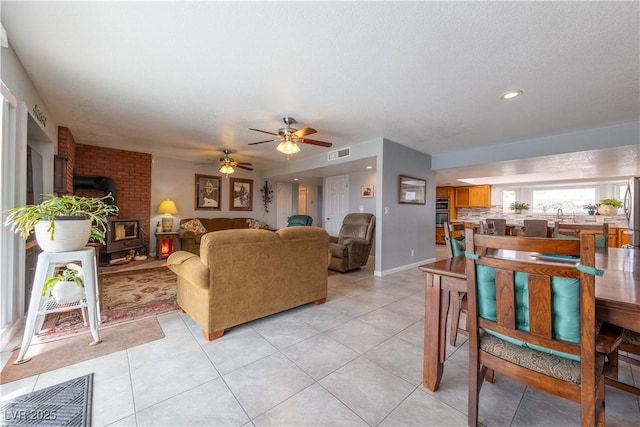 tiled living room with ceiling fan and a wood stove