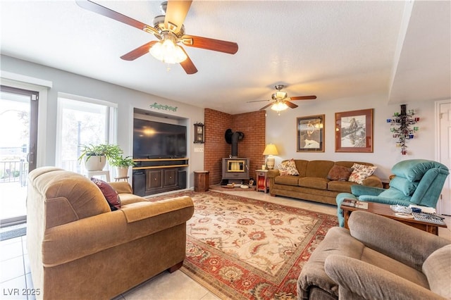 living room featuring light tile patterned floors, a textured ceiling, ceiling fan, and a wood stove