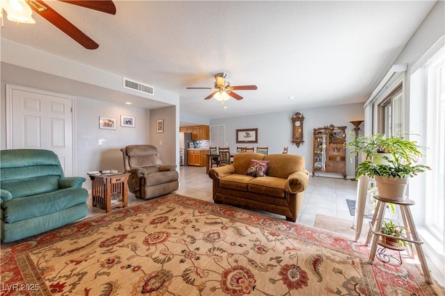 tiled living room with a textured ceiling and ceiling fan