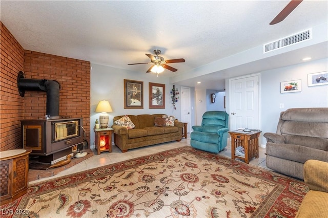 living room with a wood stove, a textured ceiling, and ceiling fan