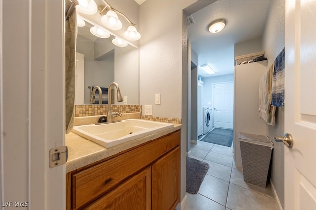 bathroom featuring washing machine and dryer, vanity, tile patterned floors, and decorative backsplash