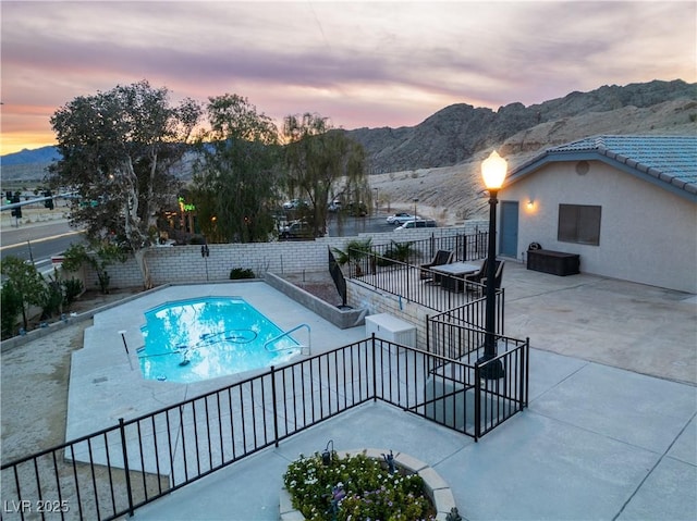 pool at dusk with a mountain view and a patio area