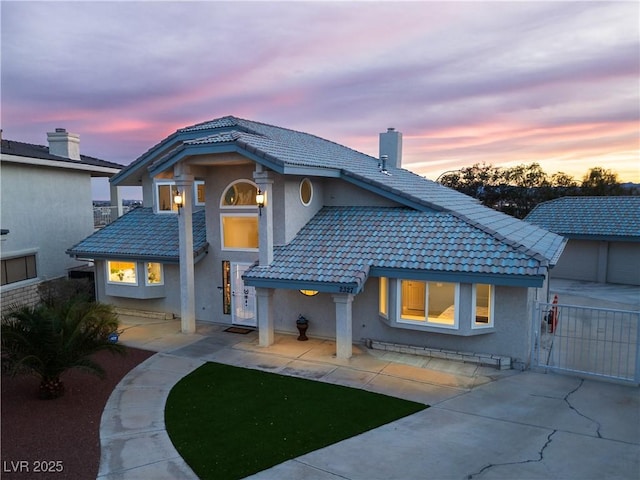 back house at dusk featuring a patio