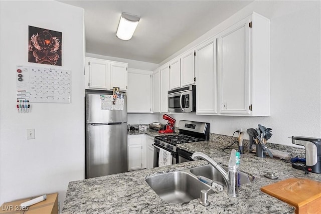 kitchen featuring white cabinets, appliances with stainless steel finishes, sink, and light stone countertops