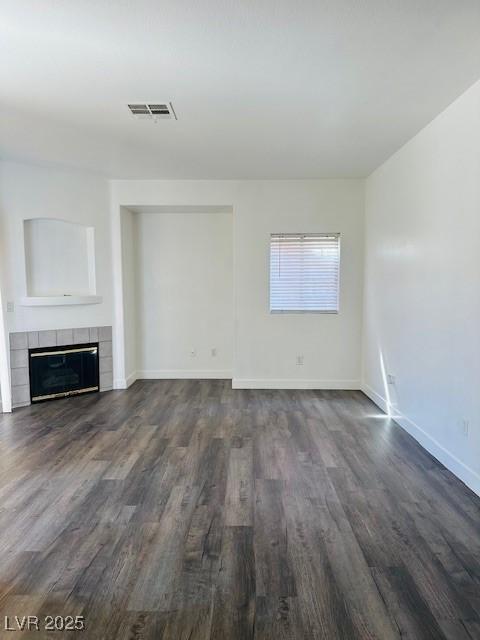 4730 E Craig Rd Unit 1172, Las Vegas, NV 89115 - unfurnished living room with dark wood-style flooring, a tiled fireplace, and baseboards