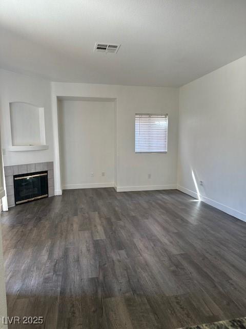 4730 E Craig Rd Unit 1172, Las Vegas, NV 89115 - unfurnished living room featuring dark wood-style flooring, a tiled fireplace, and baseboards