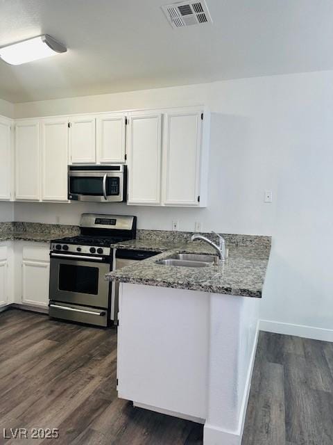 4730 E Craig Rd Unit 1172, Las Vegas, NV 89115 - kitchen with appliances with stainless steel finishes, a peninsula, a sink, white cabinetry, and dark stone countertops