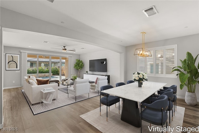 dining room with hardwood / wood-style floors and ceiling fan with notable chandelier