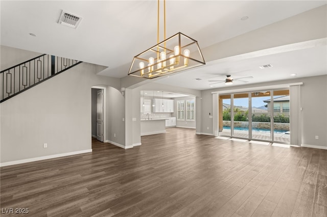 unfurnished living room featuring sink, ceiling fan with notable chandelier, and dark hardwood / wood-style floors