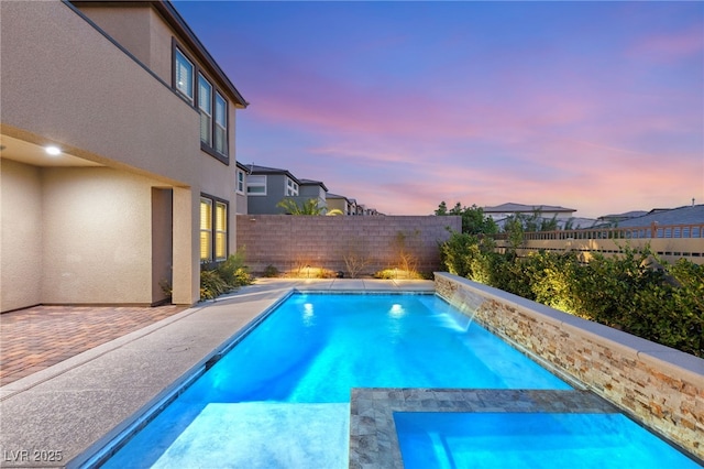 pool at dusk featuring a patio area