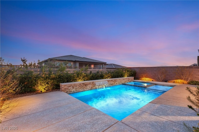 pool at dusk featuring an in ground hot tub, pool water feature, and a patio