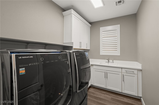 clothes washing area featuring cabinets, washer and dryer, sink, and dark hardwood / wood-style flooring