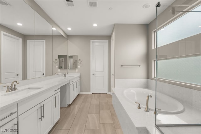 bathroom featuring vanity and tiled bath