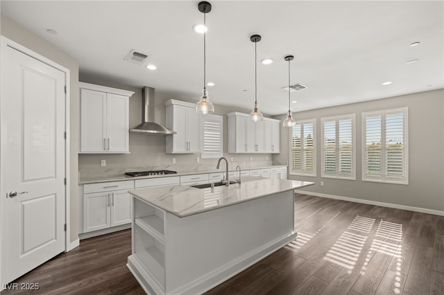 kitchen featuring an island with sink, wall chimney exhaust hood, sink, and white cabinets