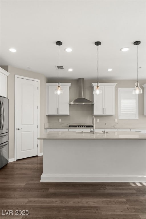 kitchen with white cabinetry, hanging light fixtures, and wall chimney range hood