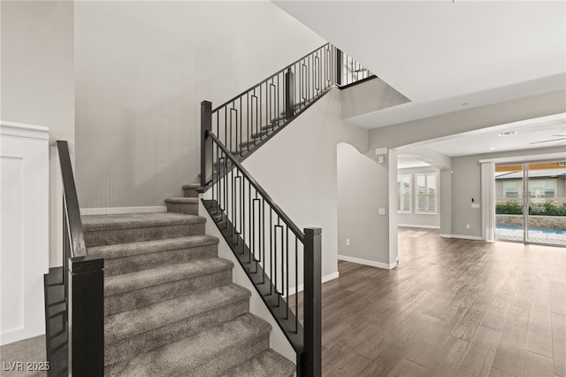 stairway with hardwood / wood-style floors and a high ceiling