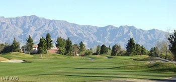 view of community featuring view of golf course, a yard, and a mountain view