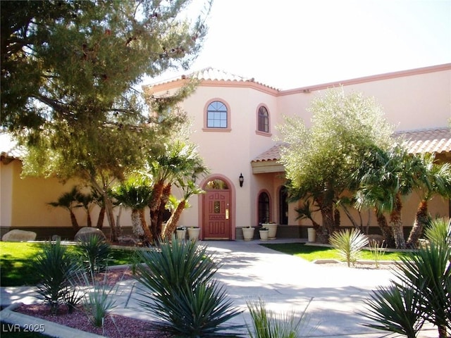 mediterranean / spanish-style home with a tiled roof and stucco siding