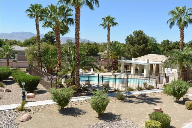 pool with a patio area, fence, and a mountain view