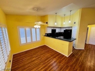 kitchen featuring ceiling fan, a peninsula, dark countertops, dark wood finished floors, and decorative light fixtures