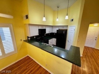 kitchen featuring dark wood-style floors, dark countertops, high vaulted ceiling, a peninsula, and fridge