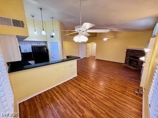 kitchen with wood finished floors, dark countertops, a fireplace with flush hearth, and visible vents