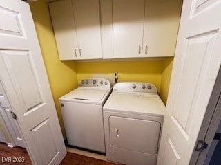 laundry area with dark wood-type flooring, washing machine and clothes dryer, and cabinet space