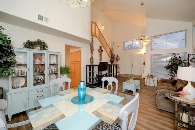 dining space with hardwood / wood-style floors, high vaulted ceiling, and a chandelier