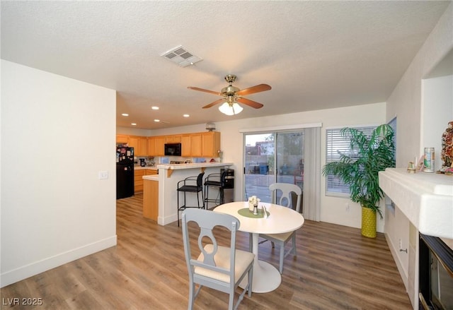 dining area with ceiling fan, light hardwood / wood-style flooring, and a textured ceiling