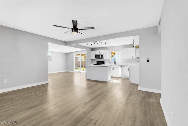 unfurnished living room featuring sink, light hardwood / wood-style flooring, and ceiling fan