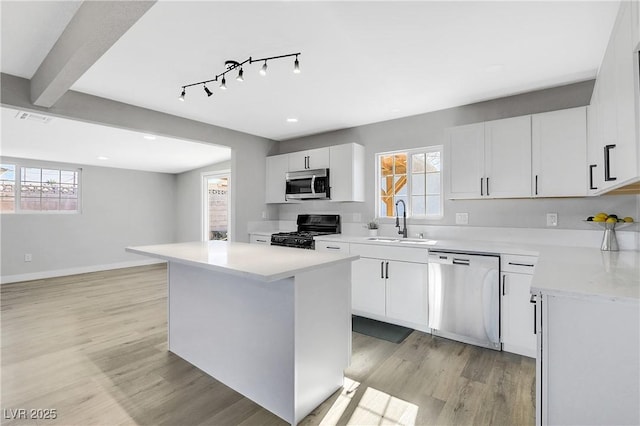 kitchen featuring sink, white cabinetry, a center island, stainless steel appliances, and light hardwood / wood-style floors