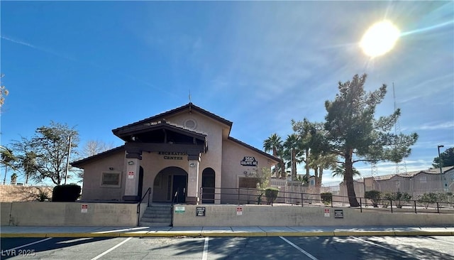 view of front of house featuring a fenced front yard, uncovered parking, and stucco siding