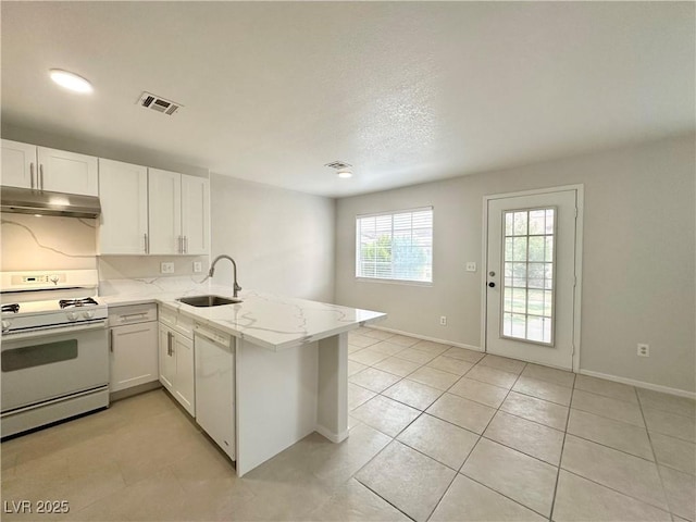 kitchen featuring white appliances, visible vents, a peninsula, under cabinet range hood, and a sink