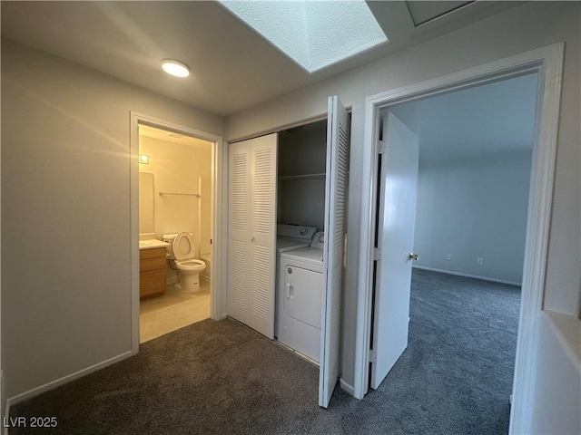 hallway featuring dark colored carpet, washer and clothes dryer, and baseboards