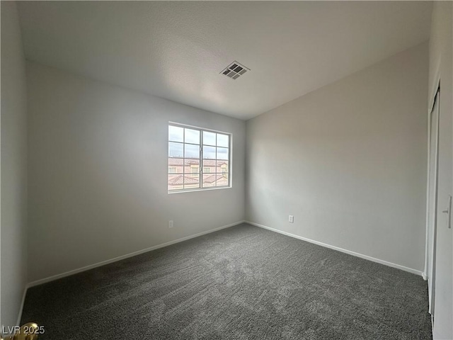 unfurnished room with dark carpet, visible vents, and baseboards