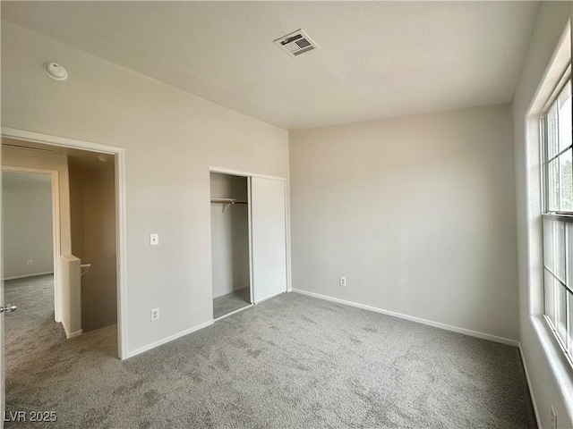 unfurnished bedroom featuring carpet floors, baseboards, visible vents, and a closet