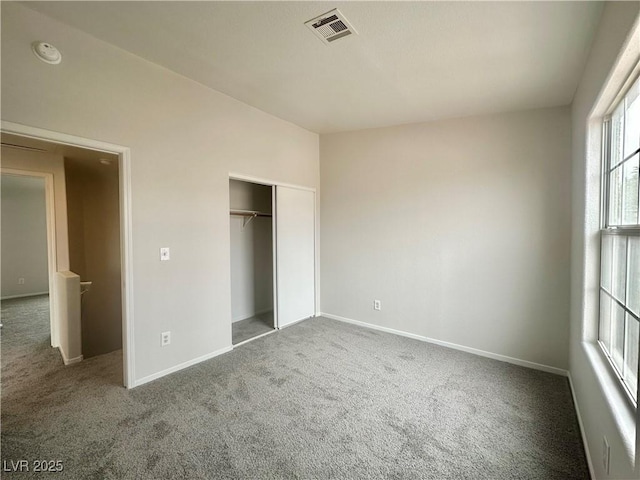 unfurnished bedroom with carpet, a closet, visible vents, and baseboards