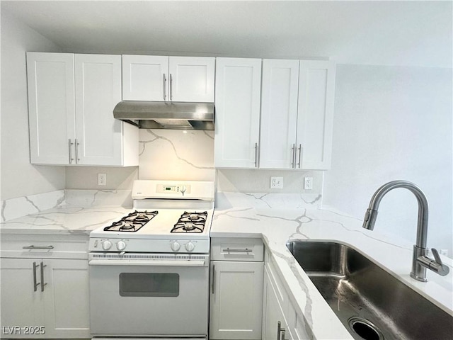 kitchen featuring under cabinet range hood, white gas range, white cabinets, and a sink