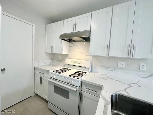 kitchen with under cabinet range hood, white gas range oven, light stone counters, and white cabinets