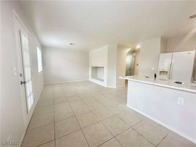 empty room featuring a textured ceiling, baseboards, and light tile patterned floors