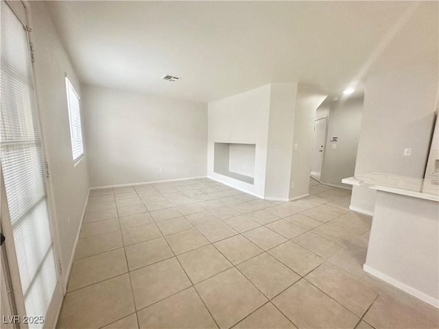 empty room featuring light tile patterned flooring, visible vents, and baseboards